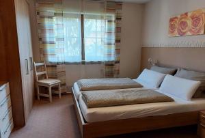 a bedroom with a bed with a chair and a window at Gästehof - Weinbau Säger in Nordheim