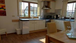 a kitchen with white cabinets and a table with chairs at Gästehof - Weinbau Säger in Nordheim