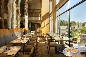 un restaurante con mesas, sillas y ventanas grandes en Oubaai Hotel Golf & Spa en George