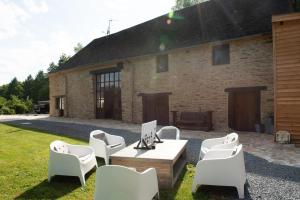 um pátio com cadeiras brancas, uma mesa e um edifício em Veyrinas 43 em Saint-Yrieix-la-Perche