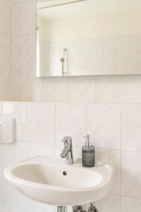 a white bathroom with a sink and a mirror at Hip & Minimalist meets Historical Old Town in Pirna