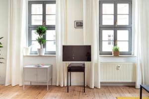 a living room with a tv and two windows at Hip & Minimalist meets Historical Old Town in Pirna