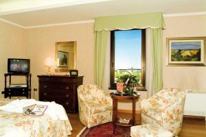 a bedroom with a bed and chairs and a window at Balletti Palace Hotel in Viterbo