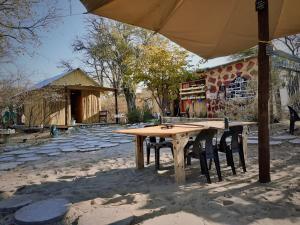 Nata的住宿－Eselbe Camp Backpackers，一把伞下的木桌和椅子