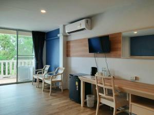 a room with a desk and chairs and a television at Karon Living Room - SHA Plus in Karon Beach