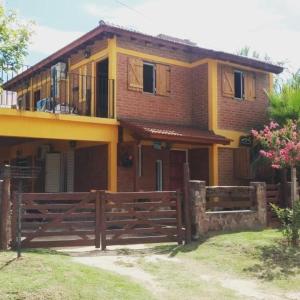 una casa con una valla de madera delante de ella en Departamento CatyDay en Mina Clavero