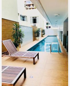 a swimming pool with a bench and a chair in a building at Loft london, estilo e praticidade no coração de Icarai in Niterói