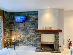 a stone fireplace with a tv on a wall at Prober Comapedrosa in Arinsal