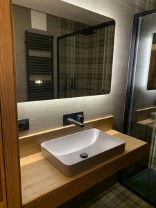 bagno con lavandino bianco e specchio di Des Alpes C Flat 11 a Madonna di Campiglio