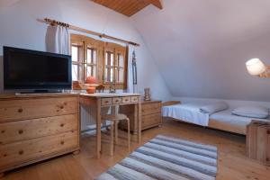 a bedroom with a desk with a television and a bed at Traditional cozy cottage BOCANKA in Nižná Boca