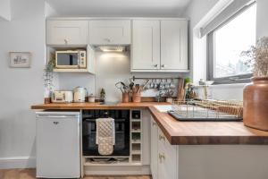 a kitchen with white cabinets and a wooden counter top at Magdalen Rest - Cosy 1 Bedr Central Flat W Fully Equipped Kitchen And Free Parking - Ginger And Gold Ltd in Norwich