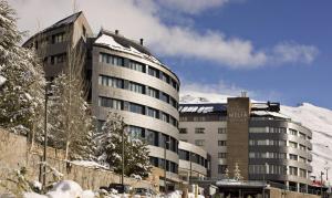 a building with a snow covered mountain in the background at Meliá Sol y Nieve in Sierra Nevada
