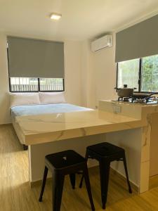 a room with a desk with a bed and two stools at Pacific Suites Guayaquil Airport in Guayaquil