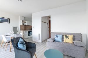 salon z kanapą, krzesłami i stołem w obiekcie Marée Tropicale - vue mer w mieście Saint-Cast-le-Guildo