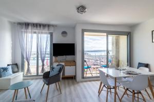 salon ze stołem, krzesłami i telewizorem w obiekcie Marée Tropicale - vue mer w mieście Saint-Cast-le-Guildo