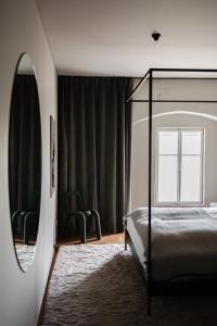 a bedroom with a canopy bed and two green chairs at MÜHLENHOF ROOMS boutique bed & breakfast in Langenlois +40 photos