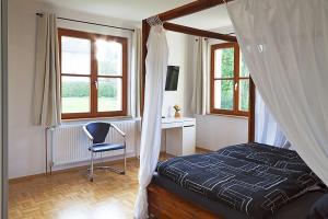 um quarto com uma cama, uma cadeira e janelas em Schwarzwaldhaus24 - Ferienhaus mit Sauna, Whirlpool und Kamin em Gemeinde Aichhalden