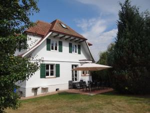 une maison blanche avec une table et un parasol dans l'établissement Schwarzwaldhaus24 - Ferienhaus mit Sauna, Whirlpool und Kamin, à Gemeinde Aichhalden