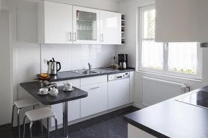 uma cozinha com armários brancos e um balcão preto em Schwarzwaldhaus24 - Ferienhaus mit Sauna, Whirlpool und Kamin em Gemeinde Aichhalden