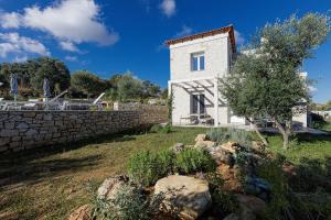 Agia Triada的住宿－Komfortvilla sensationeller Meerblick priv. Pool，白色的房子,有石墙和一棵树