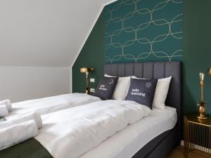 a bedroom with two beds and a green wall at limehome Klagenfurt Goessgasse in Klagenfurt