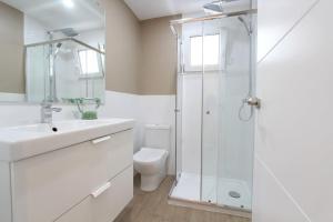La salle de bains blanche est pourvue d'une douche et de toilettes. dans l'établissement Apartamento Cuarzo, à Séville