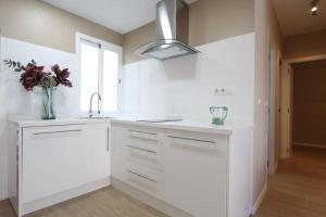 - une cuisine blanche avec un évier et un vase de fleurs dans l'établissement Apartamento Cuarzo, à Séville