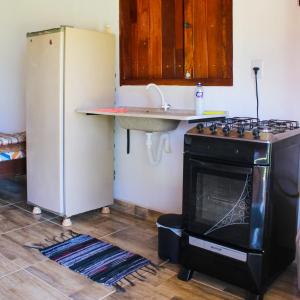a kitchen with a stove and a sink and a refrigerator at Chalé RURAL São Thomé das Letras Sobradinho até 3 pessoas in São Thomé das Letras