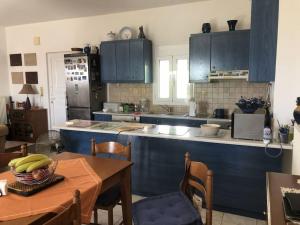 een keuken met blauwe kasten en een tafel met een kom erop bij gemütliche Villa Mailin priv. Pool schöne Aussicht in Skouloúfia