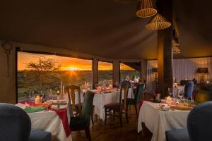 una sala da pranzo con tavoli e sedie e vista sul tramonto di Mahali Mzuri ad Aitong