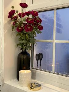 a black vase with red roses and a candle on a window at Touchwood in Isleworth