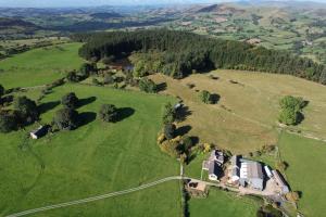 an aerial view of a house in a field at The Barn at Pentregaer Ucha, with tennis court and lake in Oswestry