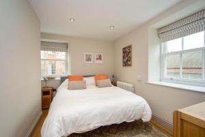 um quarto com uma cama branca e 2 janelas em Stylish two bed flat, city centre, free parking em Wells