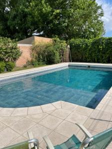 una piscina con 2 sillas de jardín junto a ella en Habitación en casa estilo campo en Luján de Cuyo