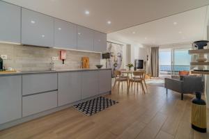 a kitchen with white cabinets and a dining room at The View House - Sesimbra in Sesimbra