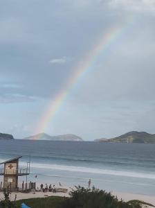 una playa con gente de pie en la arena y el agua en COBERTURA DUPLEX NA PRAIA, en Cabo Frío