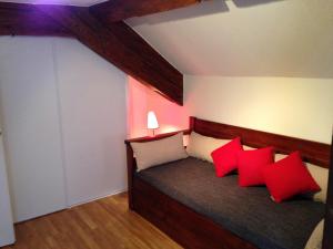 una camera da letto con un letto con cuscini rossi e bianchi di Gîte 4* Duplex centre historique Riquewihr a Riquewihr