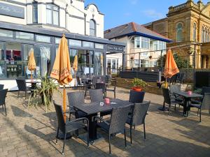 an outdoor patio with tables and chairs and umbrellas at Dukes Folly Hotel in Southport