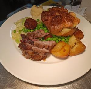 a white plate of food with meat and peas at Dukes Folly Hotel in Southport