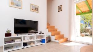 a living room with a flat screen tv and stairs at Holiday house Sunshine in Jelsa