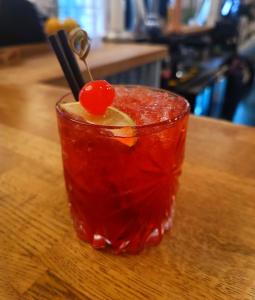 a red drink with a cherry on a wooden table at Dukes Folly Hotel in Southport