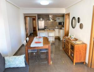 ein Wohnzimmer mit einem Tisch und einer Küche in der Unterkunft Renovated Apartment Steps Away from the Beach in Cullera