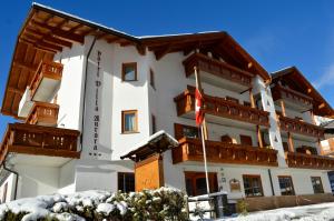 duży biały budynek z drewnianymi balkonami w śniegu w obiekcie Hotel Villa Aurora w mieście San Martino di Castrozza