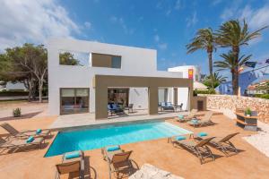 a villa with a swimming pool in front of a house at VILLA NOKA in Cala en Blanes