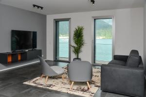 een woonkamer met een bank en stoelen en een tv bij Front Lake Apartment Meli With View Feel Ticino Feel Home in Melide