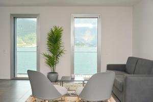 een woonkamer met 2 witte stoelen en een bank bij Front Lake Apartment Meli With View Feel Ticino Feel Home in Melide