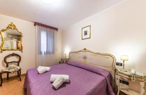 1 dormitorio con 1 cama morada y 2 toallas en Ca' Leon D'Oro, en Venecia