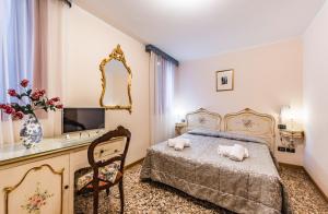 um quarto com uma cama, um espelho e uma cadeira em Ca' Leon D'Oro em Veneza