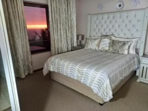 a bedroom with a white bed with a large window at 110 Bay View in Brenton-on-Sea