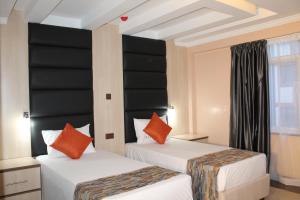two beds in a room with black and orange pillows at Airport Landing Hotel in Nairobi